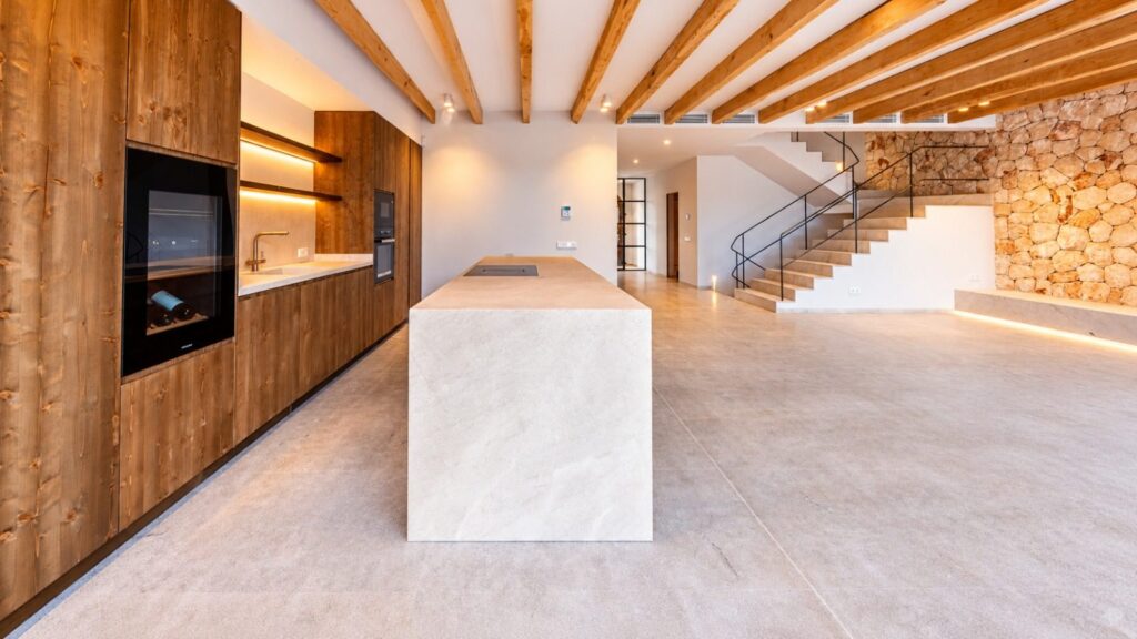 Cocina de diseño contemporáneo con isla de piedra, vinoteca y escalera al fondo